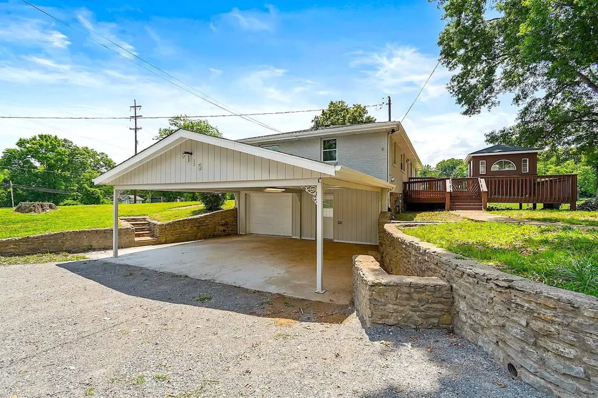 A welcoming exterior image featuring the house, a cozy deck, and a carport, surrounded by greenery. The deck invites moments spent together—whether starting the day with coffee or relaxing after exploring the city—while the natural surroundings reinforce the balance of privacy and accessibility.