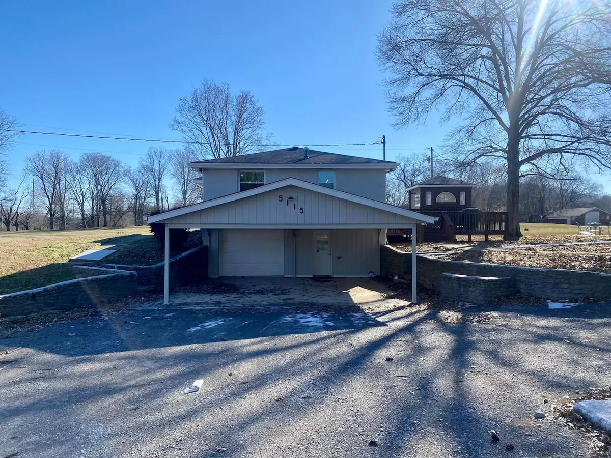 The image showcases the exterior of the house, featuring the welcoming facade, a large tree, and a visible playground structure in the yard. The scene suggests ample space for gatherings and outdoor play, with a porch area that hints at relaxing or socializing outdoors.