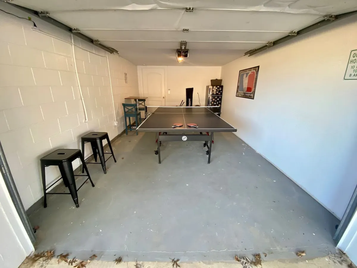 A dedicated ping-pong room with a ping pong table as the focal point, complemented by bar stools for spectators or resting players and bright wall art that adds a playful touch to the space. The room is designed for energetic games and social interaction.
