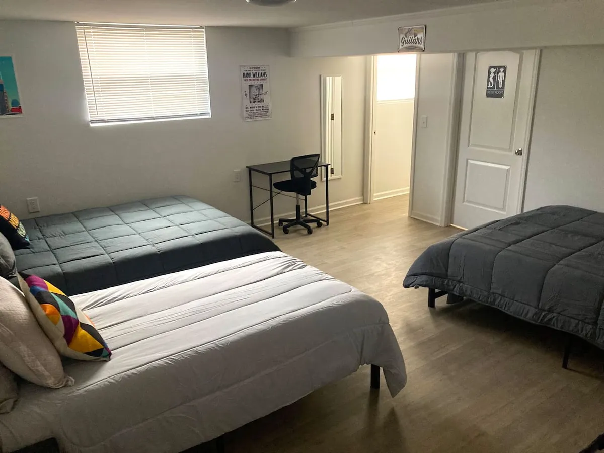 A shared bedroom space with two beds, a desk with a chair, a large mirror, and decorative pillows. The room feels comfortable and flexible, supporting both rest and social moments. Its layout hints at adaptability for different group configurations, from families to friends.